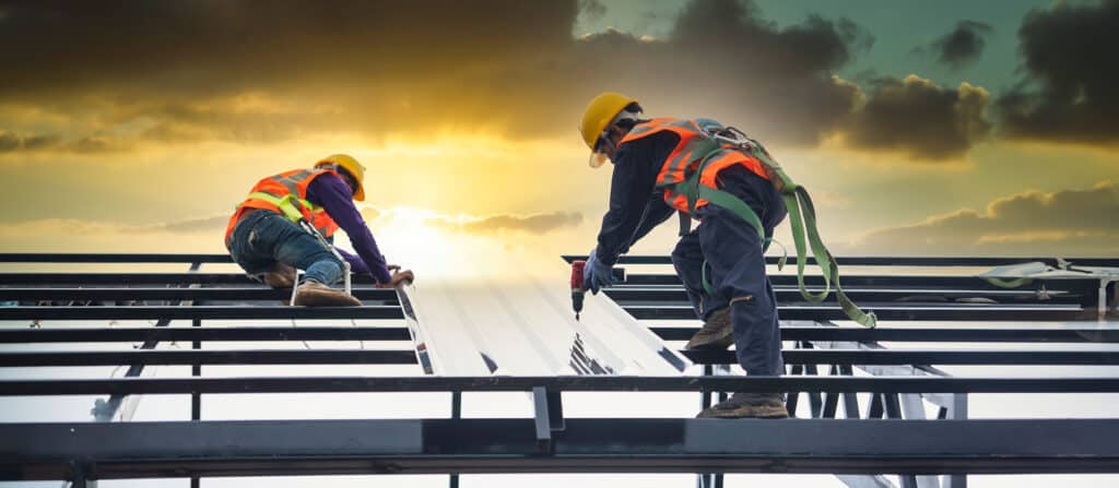 construction workers wear safety straps while working on the roof structure of the building