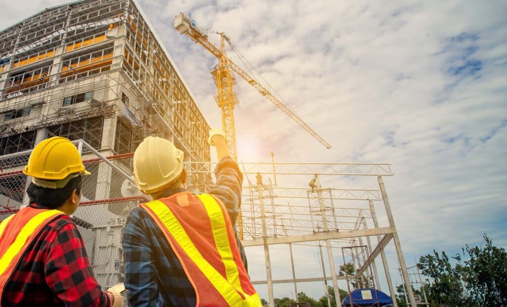 Construction worker and engineer wearing safety gear looking for