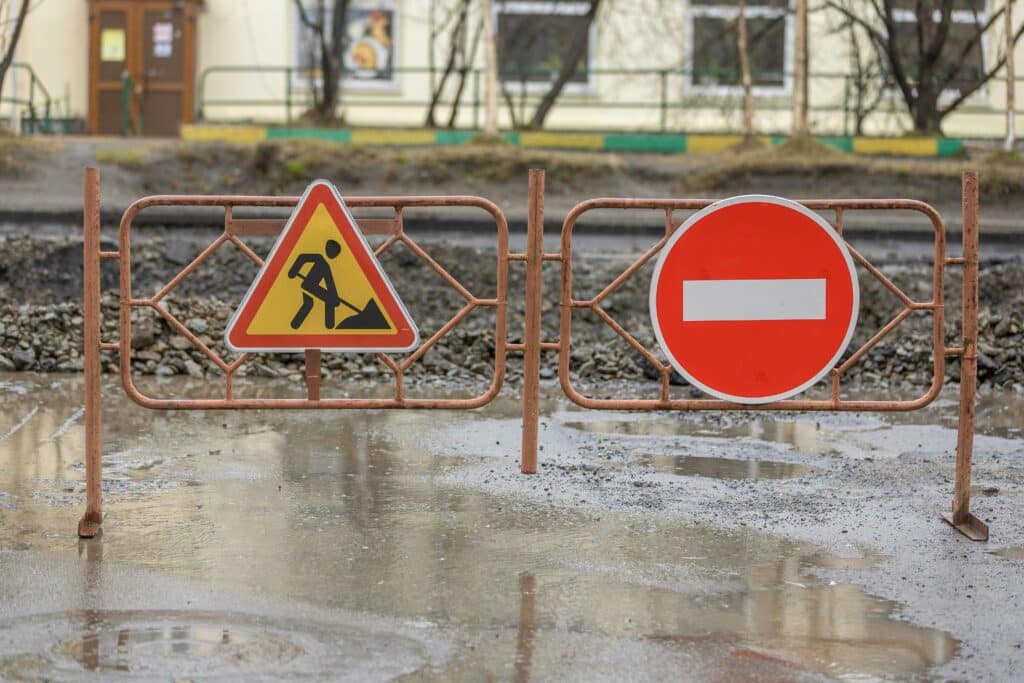 Construction road barrier with roadwork warning and no-entry signs at an active worksite