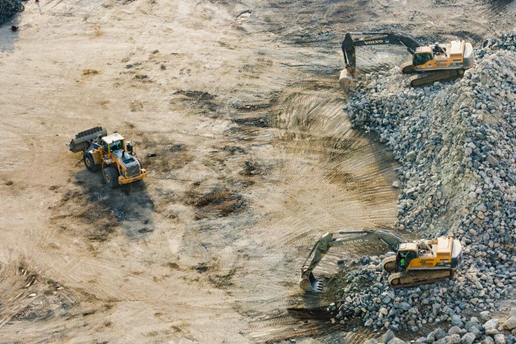 Aerial view of excavators and a wheel loader moving crushed stone at an industrial construction site
