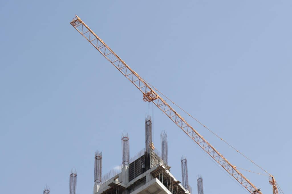 Yellow tower crane lifting materials at an active construction site.