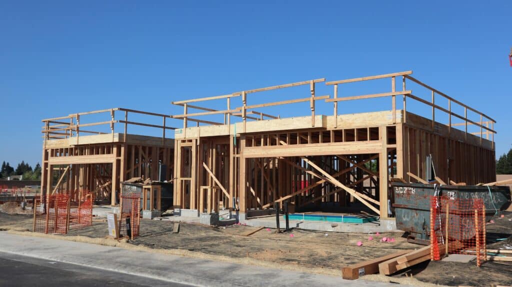 Wood-framed commercial building under construction with exposed beams and jobsite safety barriers visible